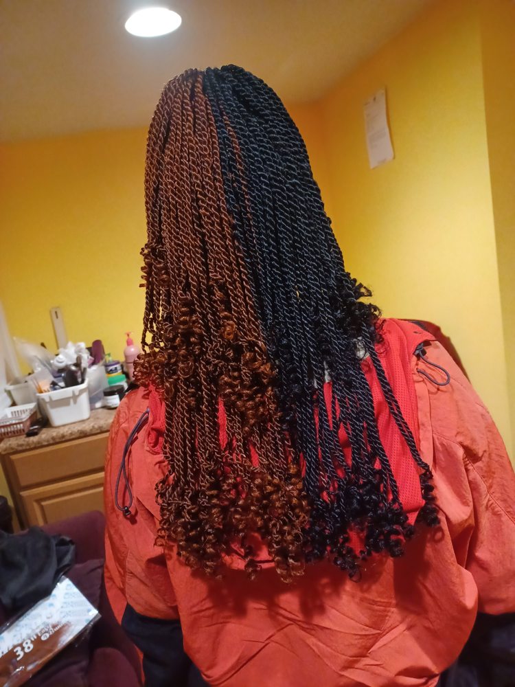Woman in a red top with long, reddish-brown micro-braids