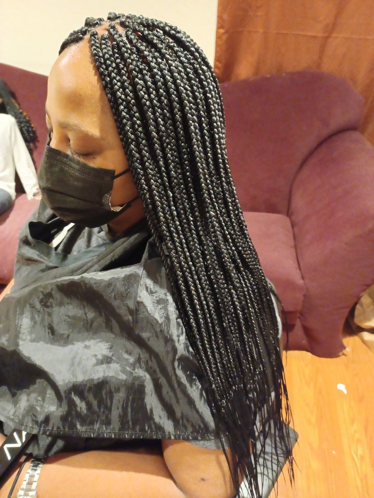 Side profile of a woman with long dark braids wearing a face mask